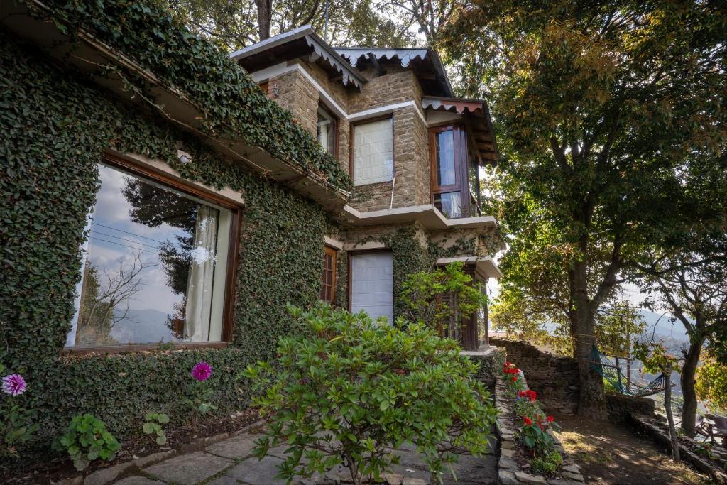 a building covered in ivy with windows and flowers at Avenida Himalayan Retreat in Mukteswar