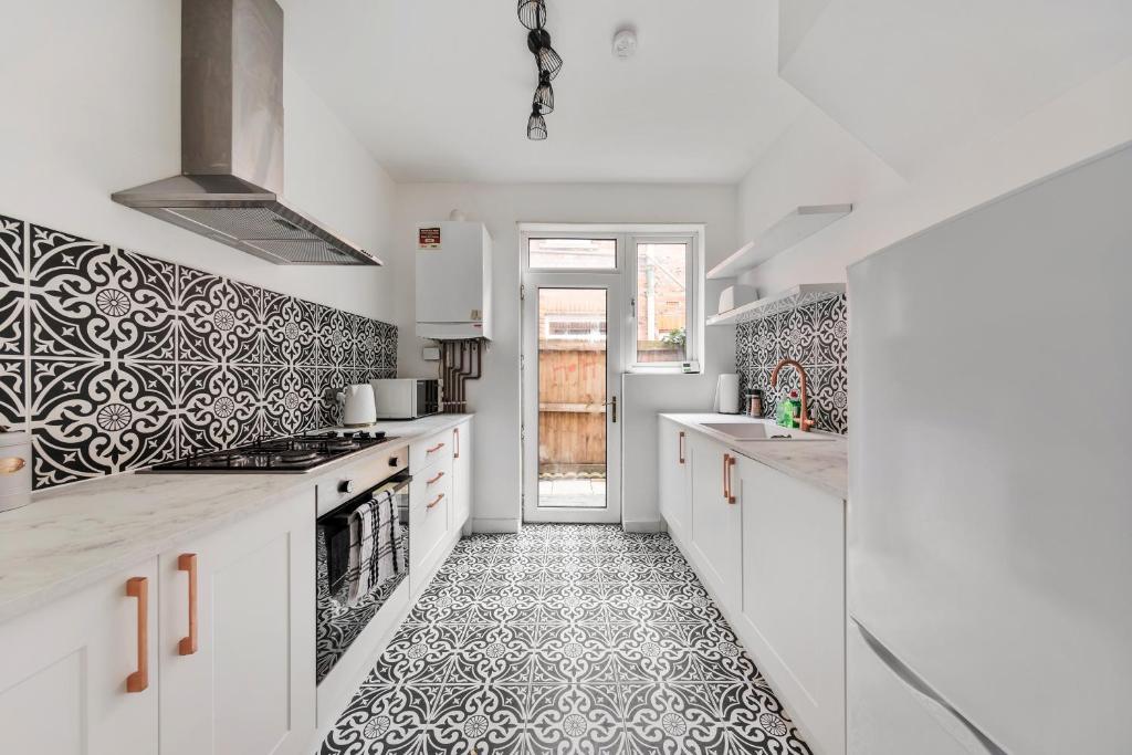 a kitchen with white cabinets and a black and white tile floor at Beautifully Modern 2-Bed Apartment w/garden in London