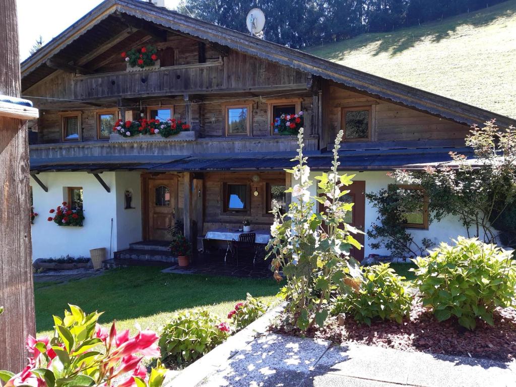 una casa de madera con flores en el patio delantero en Wildauhof - Bauernhaus, en Fügenberg