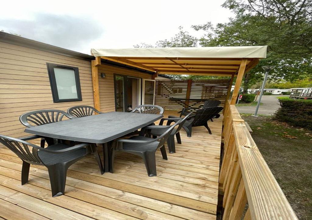 een picknicktafel en stoelen op een houten terras bij Détente-famille-lac in Biscarrosse