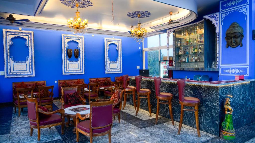 un restaurante con paredes azules y un bar con mesas y sillas en Hotel Kalyan, en Jaipur