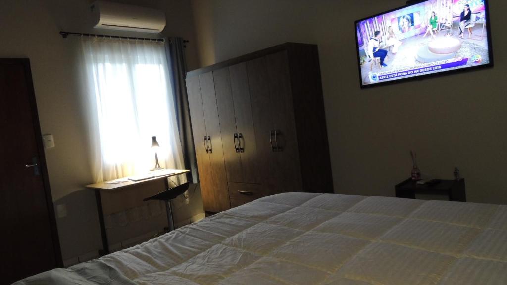 - une chambre avec un lit et une télévision murale dans l'établissement Pousada Cusco - no Centro Jaraguá do Sul - Sem Estacionamento, à Jaraguá do Sul