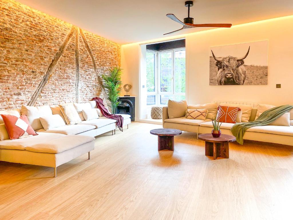 una sala de estar con 2 sofás y una pared de ladrillo en Ribera AC by Staynnapartments, en Bilbao