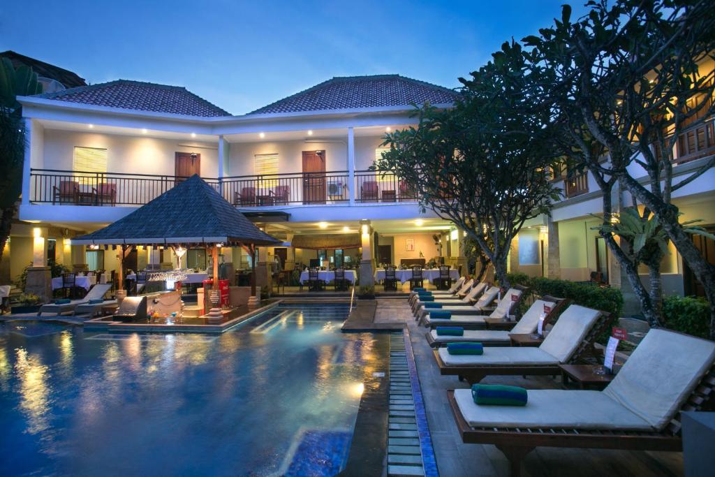 einen Pool mit Liegestühlen und ein Hotel in der Unterkunft The Niche Bali in Legian