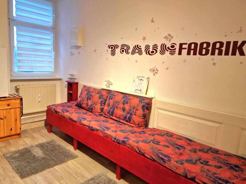 eine rote Couch in einem Zimmer mit Schild an der Wand in der Unterkunft Gästequartier mittendrin in Coswig Anhalt in Coswig