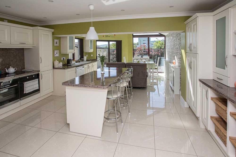 a large kitchen with white cabinets and a large island at Sleepy Rock in Dungarvan