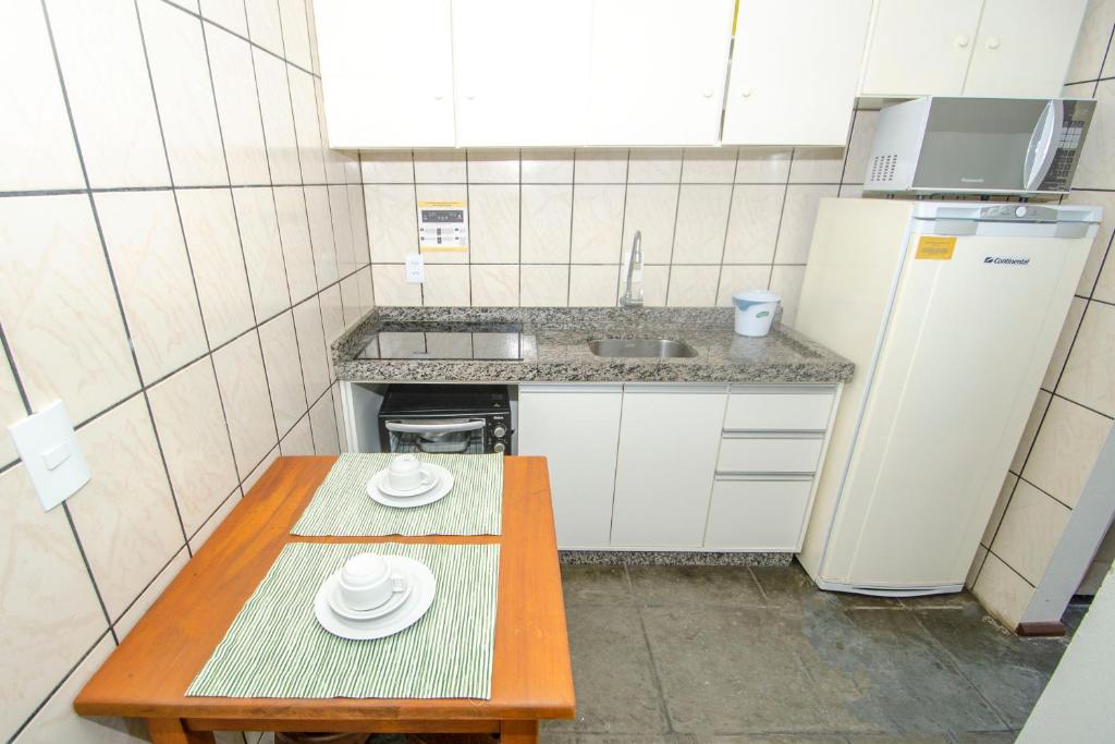 Il comprend une petite cuisine équipée d'une table et d'un réfrigérateur. dans l'établissement Residencial Primavera, à Bombinhas