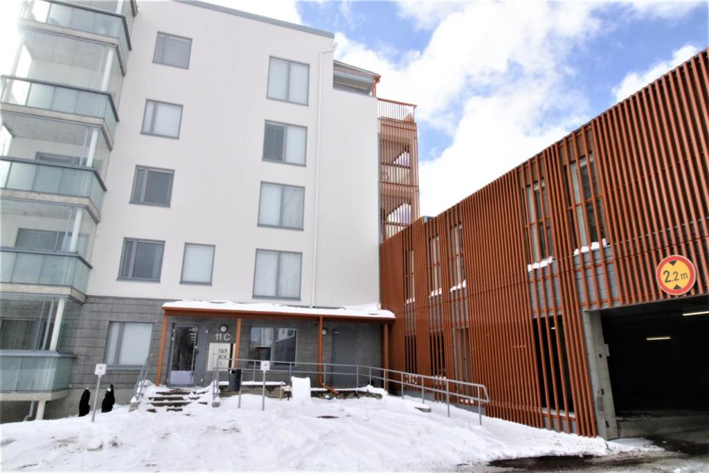 a large white building with snow in front of it at Forenom Serviced Apartments Espoo Saunalahti in Espoo