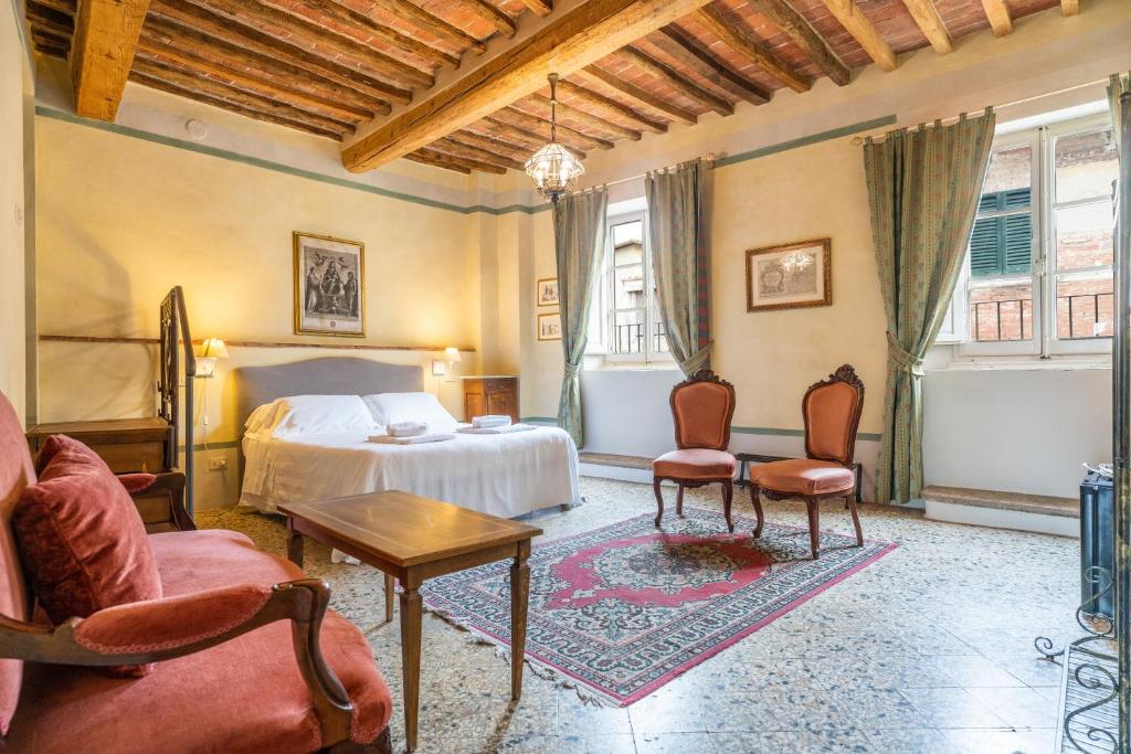 a bedroom with a bed and two chairs and a table at Palazzo Mosela Alla Porta in Montepulciano