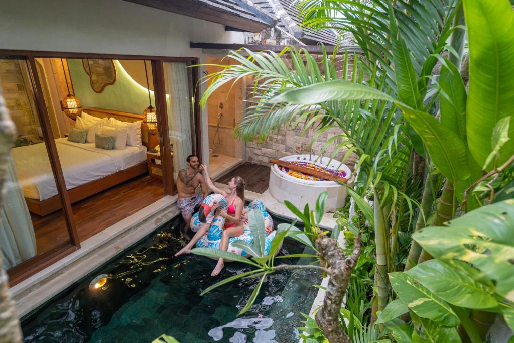 a group of people standing in a hotel room with a pond at Aksari Villa Seminyak by Ini Vie Hospitality in Seminyak