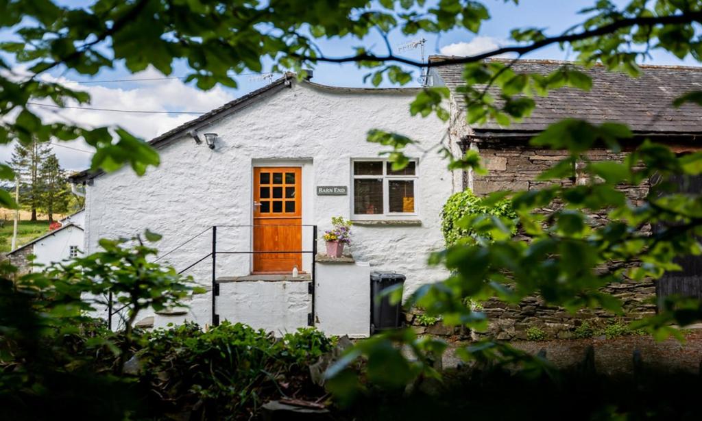 a white cottage with a orange door at Barn End in Ambleside