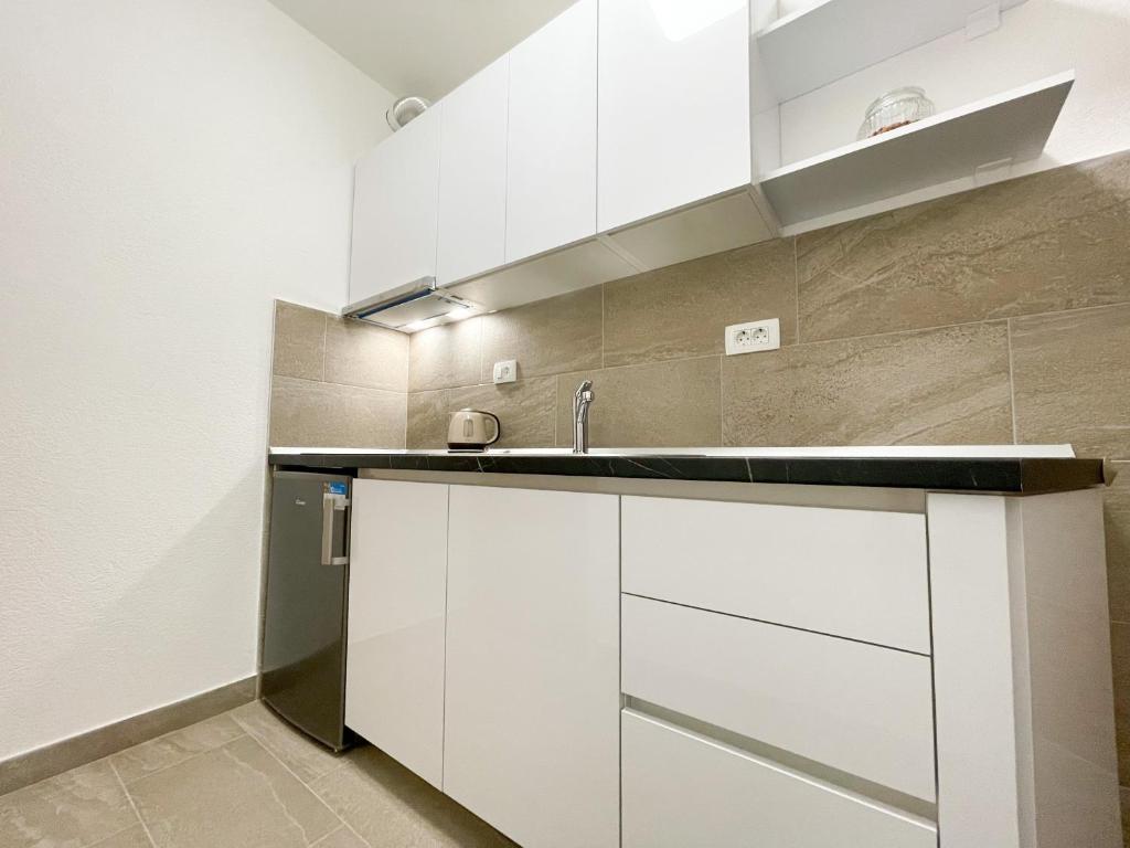 a kitchen with white cabinets and a sink at Apartments Marija Magdalena in Hvar