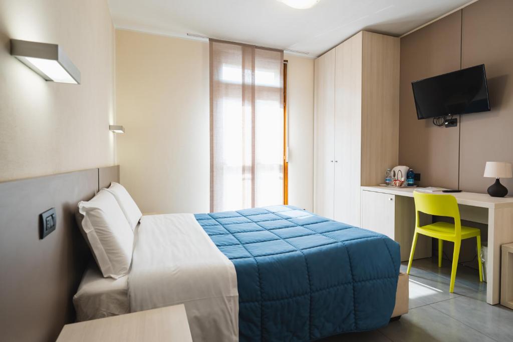 Habitación de hotel con cama y escritorio con silla amarilla en Parini Hotel, en Bosisio Parini