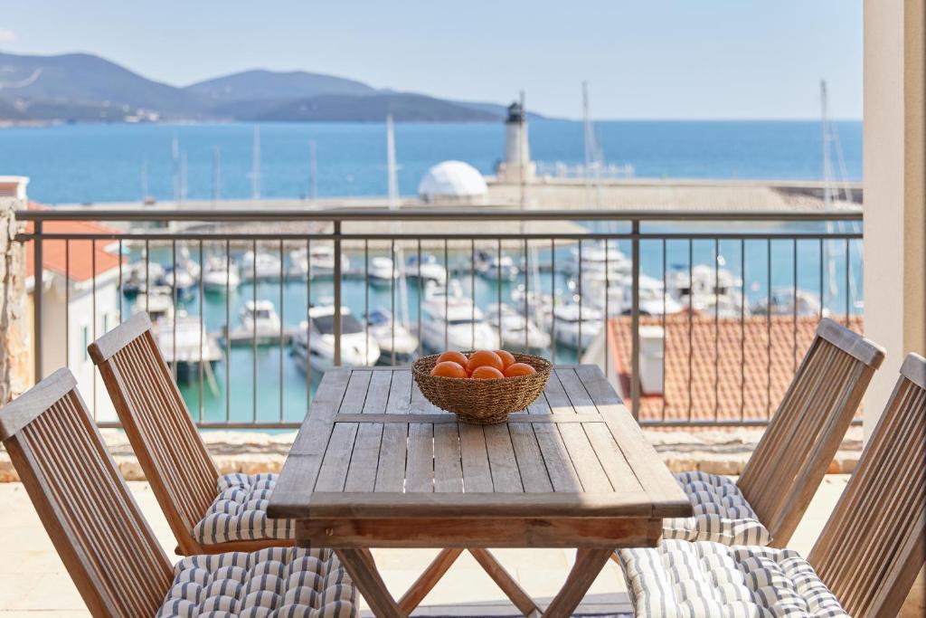 une table en bois avec un bol d'oranges sur un balcon dans l'établissement Luštica Bay Magnolia apartment with big terrace, à Tivat