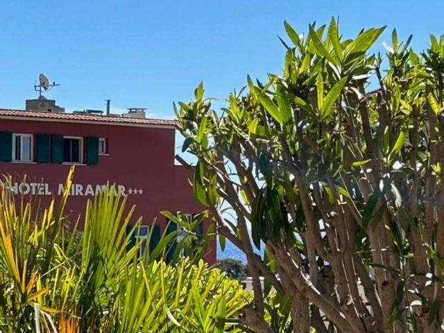 ein rotes Gebäude mit einem Baum davor in der Unterkunft Hotel Miramar in Cap d'Ail