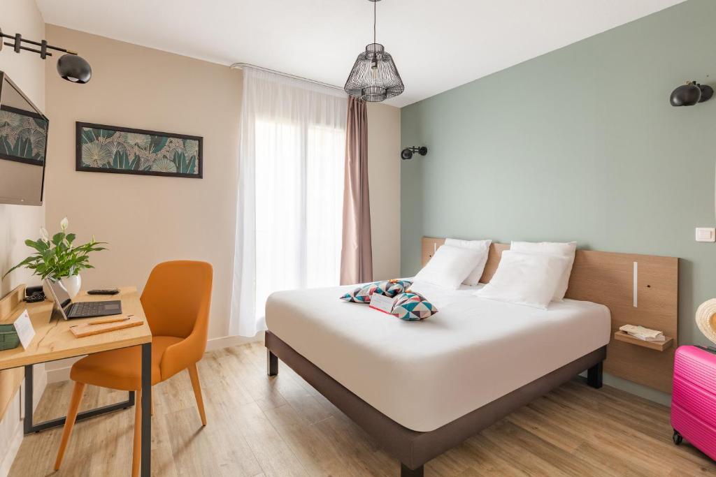 um quarto de hotel com uma cama, uma secretária e uma cadeira em Appart'City Confort Agen Centre em Agen