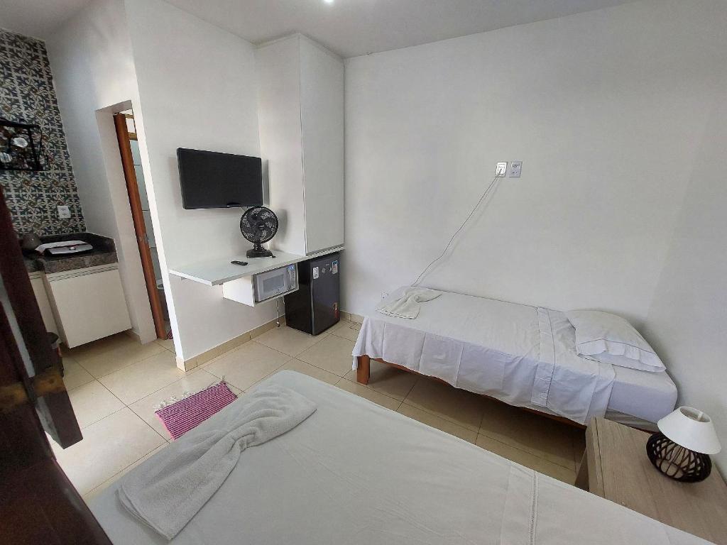 a small room with two beds and a television at Confortáveis e práticas Kitnets em Belo Horizonte in Venda Nova