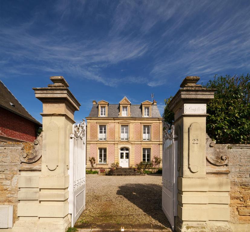 an entrance to a large house with a white gate at La Cantellerie in Courseulles-sur-Mer