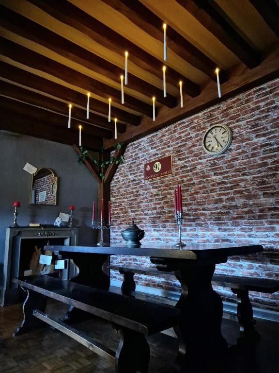 un mur en briques avec une table et une horloge sur celle-ci dans l'établissement Le Gîte Ensorcelé, à Saint-Jean-Soleymieux