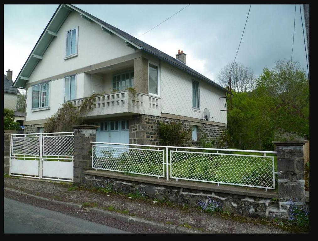 una casa blanca con una valla delante en Maison sur Rhue, en Égliseneuve-dʼEntraigues