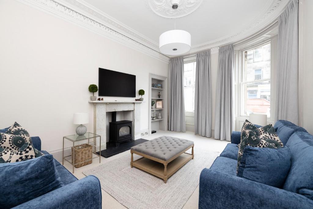 sala de estar con 2 sofás azules y chimenea en Stylish 3-Bedroom Edinburgh City Getaway, en Edimburgo