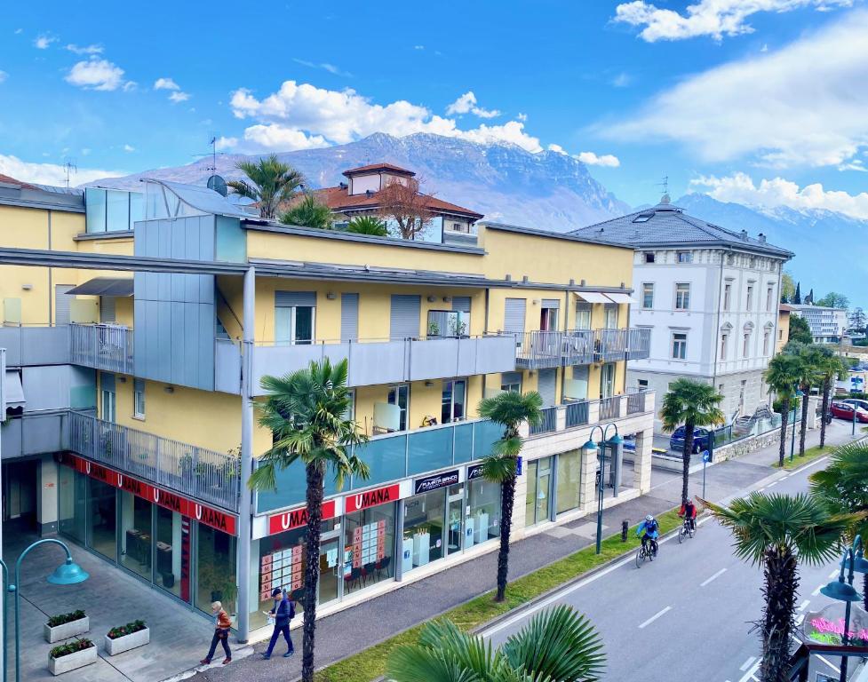 a city street with buildings and palm trees and a mountain at Riva Central Apartment - Free Parking in Riva del Garda