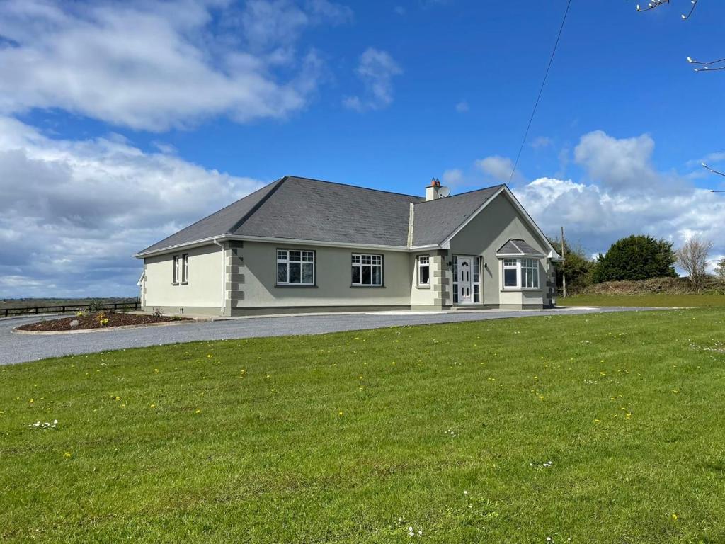 una casa blanca con un césped verde delante de ella en Ballylee en Galway