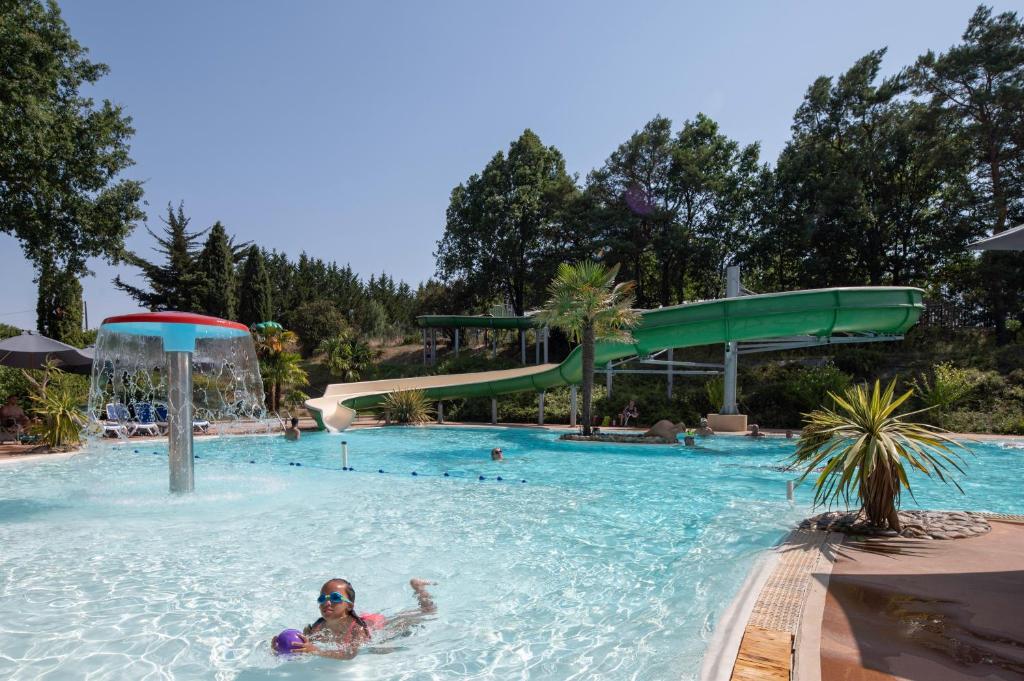 a woman swimming in a swimming pool at a resort at Camping maeva Escapades Le Domaine Aramis in Marsan