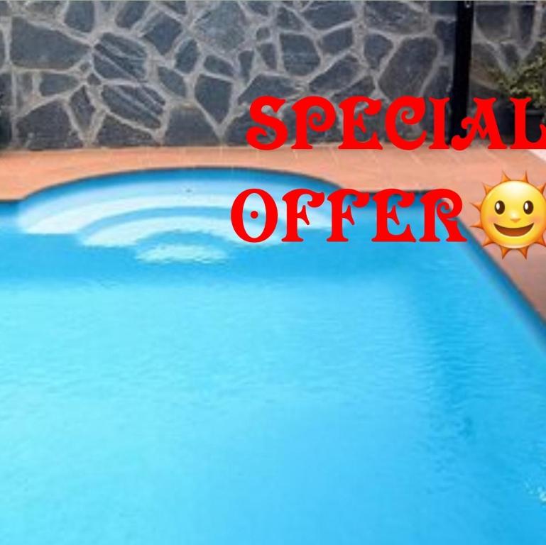 een bord met speciale aanbieding naast een zwembad bij Beautiful comfortable property Private pool with FREE HEATING Hot tub WIFI Full Kitchen air conditioning Mosquito blinds Brick BBQ in Corralejo