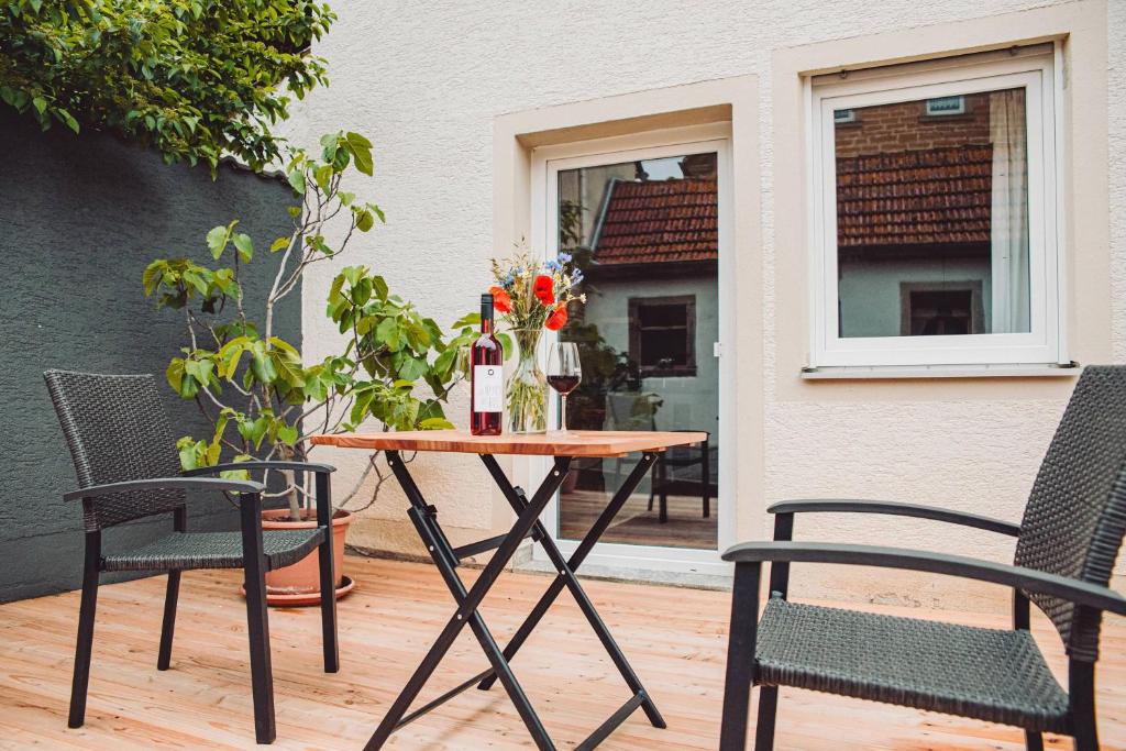 a table with two chairs and a table with wine bottles at Haus am Zabelstein in Dingolshausen