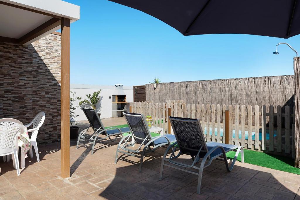 a patio with chairs and a table and a fence at Currimar in Conil de la Frontera