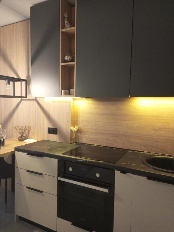 a kitchen with white cabinets and a black counter top at New loft style apartment in Uzhhorod