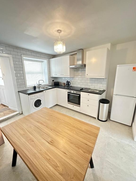 a kitchen with a wooden table and a white refrigerator at Cosy corner in Sligo