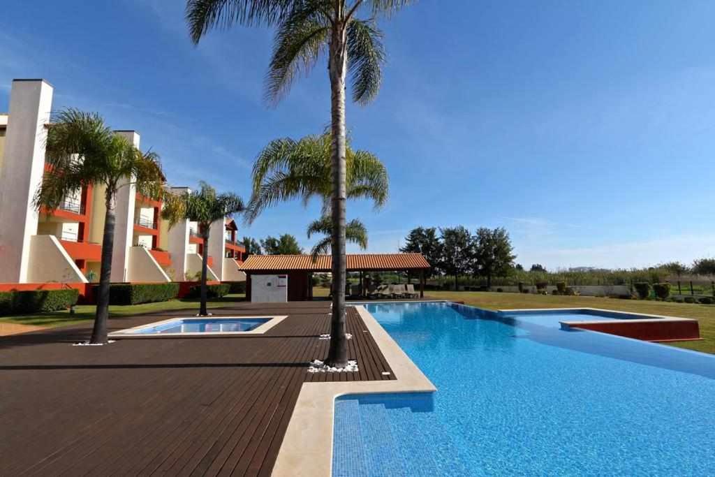 einen Pool mit Palmen neben einem Gebäude in der Unterkunft Golf Mar Village By Vilamoura Sun Vista Golfe in Vilamoura
