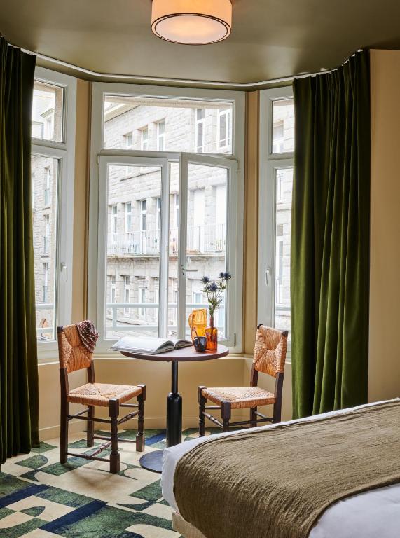 1 dormitorio con mesa, 2 sillas y ventana en Hôtel Cartier, en Saint-Malo