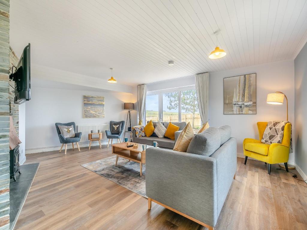 a living room with a gray couch and yellow chairs at Trewethett Farm in Forrabury