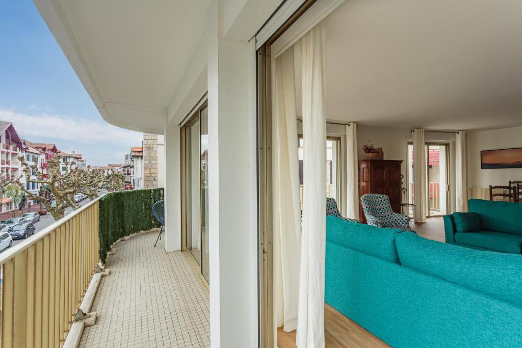 a living room with a blue couch on a balcony at Bel appartement en plein centre ville et 50 m de la grande plage in Saint-Jean-de-Luz