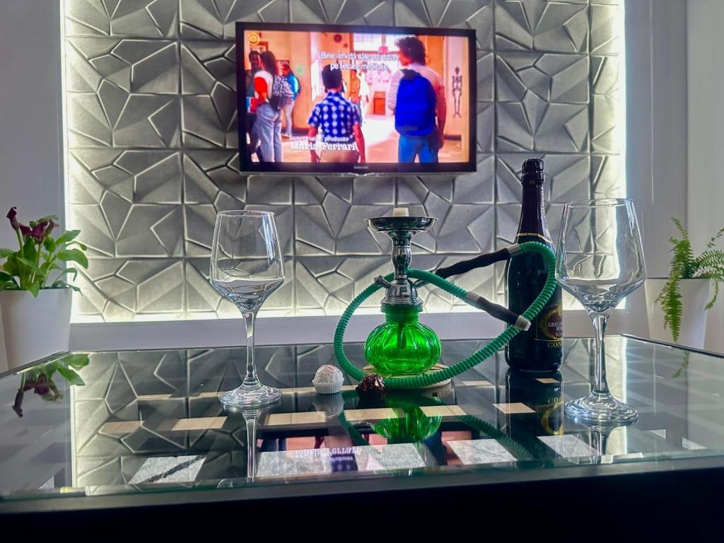 a glass table with wine glasses and a television at Confort Apartament in Ploieşti