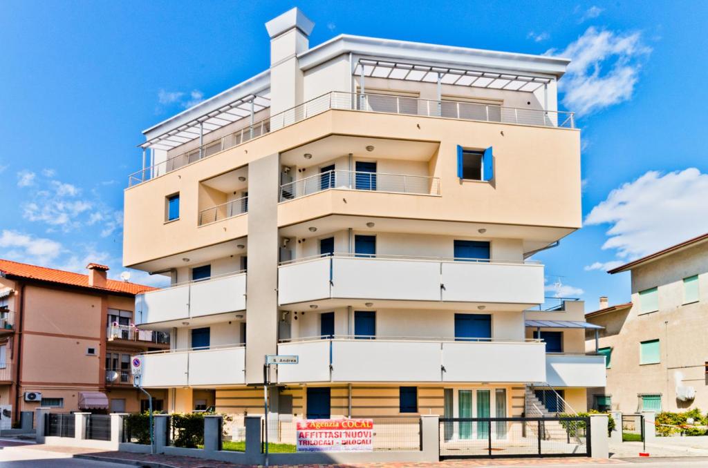 ein großes Apartmenthaus mit blauem Himmel im Hintergrund in der Unterkunft Villa Marina Apartments - Agenzia Cocal in Caorle