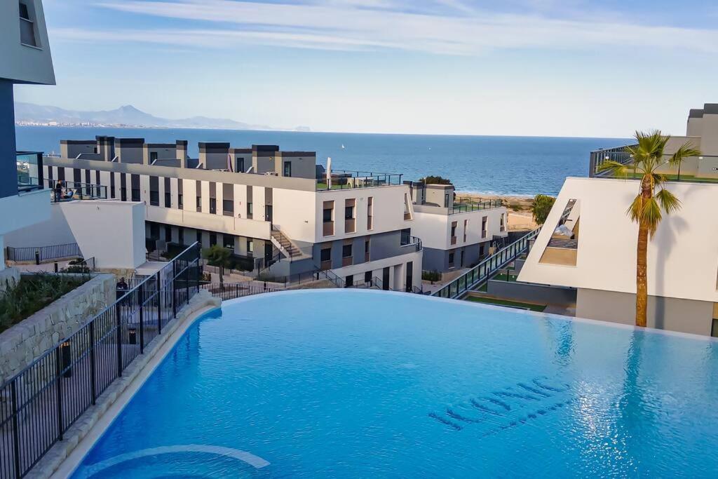 een groot zwembad naast sommige gebouwen en de oceaan bij Iconic Sea Views Luxury Apartment in Puerto Marino