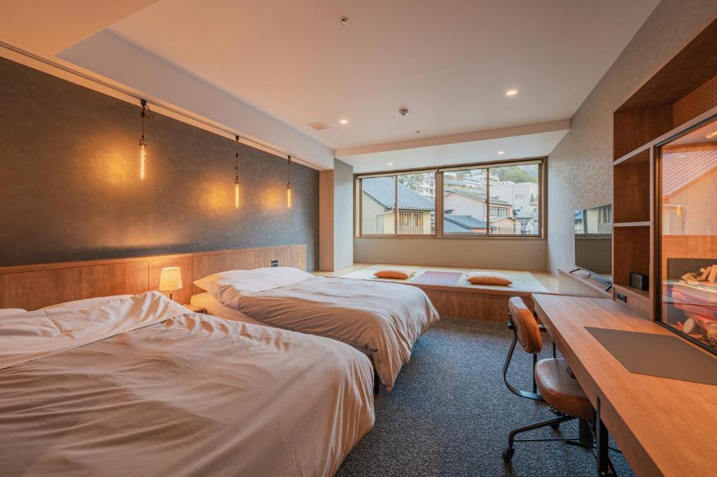 神戸市にあるHOTEL ALGOのベッド2台とデスクが備わるホテルルームです。