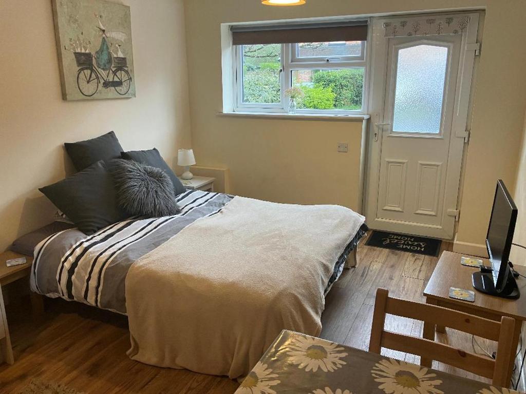 a bedroom with a bed and a desk and a window at The Garage in Wimborne Minster
