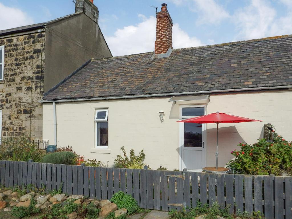 una casa blanca con un paraguas rojo y una valla en Brier Dene Middle Cottage, en Hartley