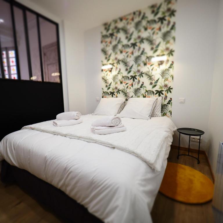 duże łóżko z białą pościelą i ręcznikami w obiekcie Appartement de charme Art Déco w mieście Vichy