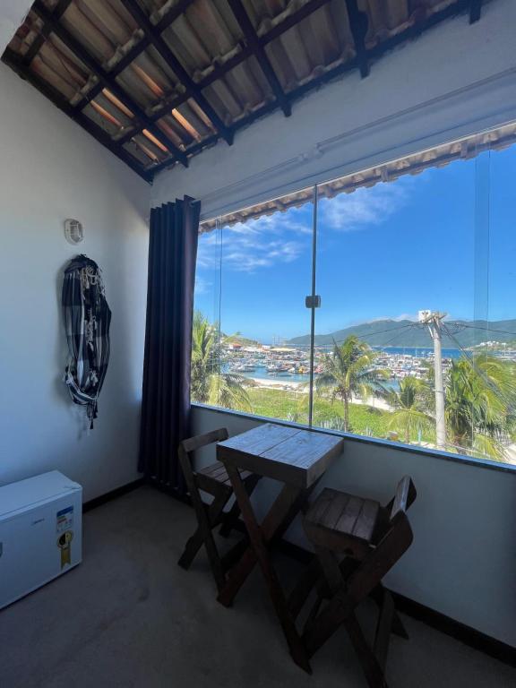 uma mesa e uma cadeira num quarto com uma grande janela em Hospedagem Pé Na Areia em Arraial do Cabo