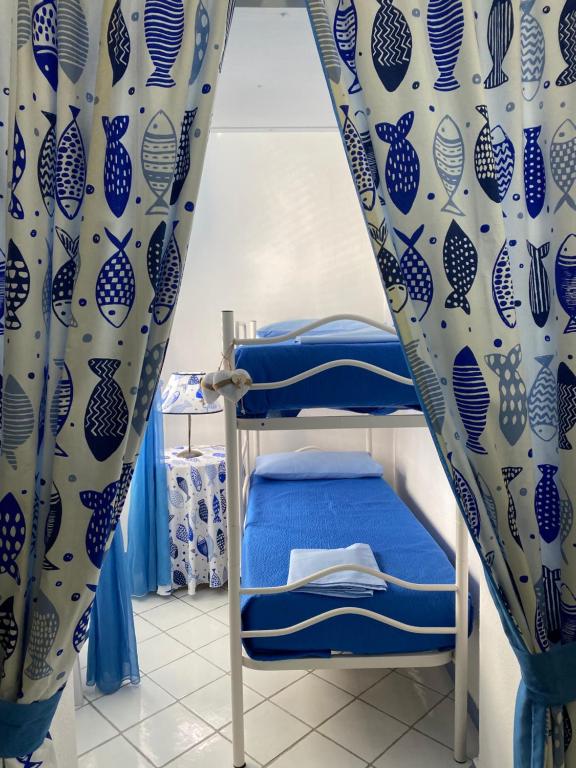 Litera en habitación con cortinas azules y blancas en Riva Destra Suite apartament, en Isquia