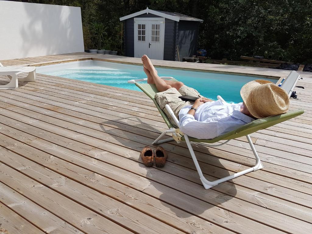 Ein Mann, der auf einem Liegestuhl neben einem Pool liegt. in der Unterkunft Maison à Tosse avec vue sur la nature in Tosse