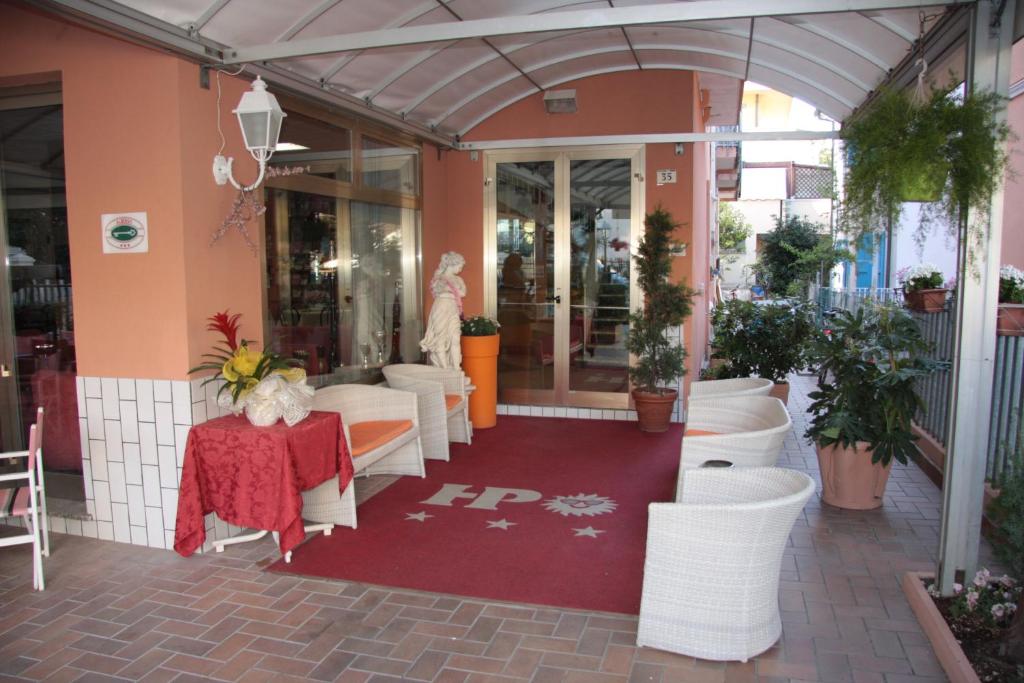 a restaurant with a red table and white chairs at Hotel Peonia in Rimini