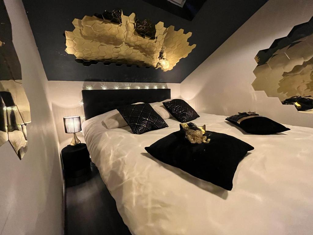 a bedroom with a large white bed with black pillows at La tentation in Berck-sur-Mer