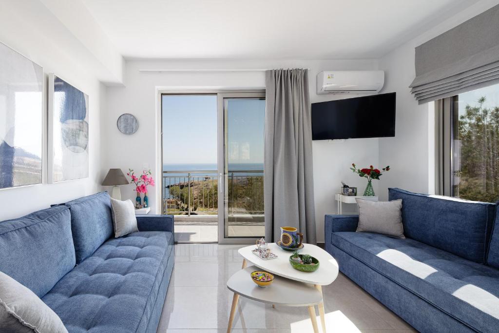 uma sala de estar com sofás azuis e vista para o oceano em Contessina del mare em Panormos Rethymno